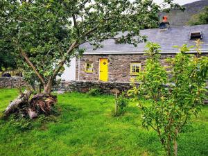 a stone house with a yellow door in a yard at Cottage Skelligs Coast, Ring of Kerry in Cahersiveen