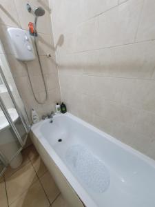 a white bath tub in a bathroom with a shower at Private rooms with shared facilities in Camden Town in London