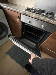 a person holding an open oven door in a kitchen at Private rooms with shared facilities in Camden Town in London