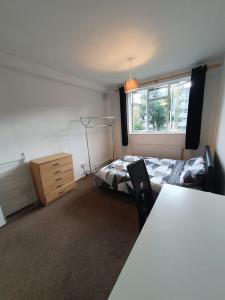 a bedroom with a bed and a dresser and a window at Private rooms with shared facilities in Camden Town in London