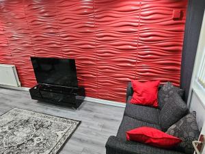a living room with a couch and a red wall at Exclusive Airbnb haven in Birmingham