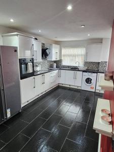 a kitchen with white cabinets and a black tile floor at Exclusive Airbnb haven in Birmingham