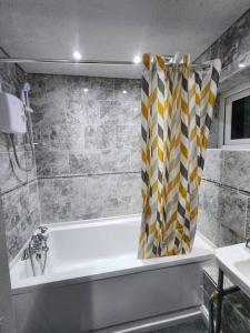 a bathroom with a tub and a shower curtain at Exclusive Airbnb haven in Birmingham