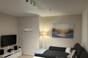 ein Wohnzimmer mit einem Sofa und einem Flachbild-TV in der Unterkunft Küstenbude Glück in Grömitz