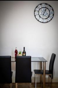 mesa de comedor con sillas y reloj en la pared en Cozy Roome @ Wallsend B, en Old Walker
