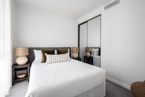 a bedroom with a white bed and a large mirror at Birch Apartments by the Lake in Canberra