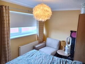 una camera con letto, sedia e lampadario a braccio di Levens Terrace, Barrow Spa Therapy a Barrow in Furness