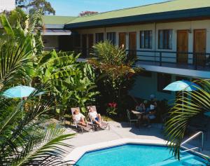 a couple of people sitting in chairs by a swimming pool at Soluxe el sesteo in San José