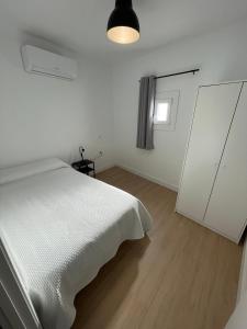 ein weißes Schlafzimmer mit einem weißen Bett und einem Fenster in der Unterkunft Mirador Templario in Jerez de los Caballeros