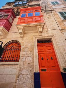 a building with two red doors and two windows at 150 years old Maltese Townhouse: Dar Emanuela in Cospicua