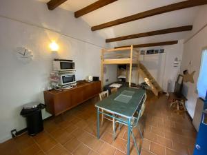 a room with a table and a desk with a microwave at Mazet avec jardin in Saint-Bauzille-de-Putois