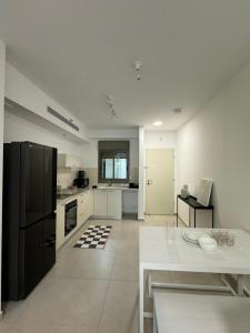 a kitchen with a black refrigerator and a white table at Sunset suite - step from the beach in Ashkelon