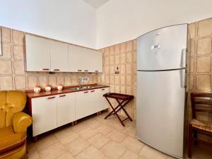 cocina con armarios blancos y nevera en Casa per vacanze Ludovica, en Avetrana