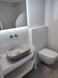 uma casa de banho branca com um lavatório e um WC em Sifnos "Sofia apartments" sea view em Faros