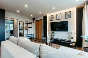 ein Wohnzimmer mit einem Sofa und einem TV in der Unterkunft Happy Place - Happy Apartamenty Mielec in Mielec