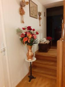 a vase of flowers on a stand in a hallway at chambre d'hôte "Chambre dans une maison pleine de vie" in Saint-Rémy-lès-Chevreuse