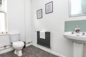 a white bathroom with a toilet and a sink at Spacious and Comfy 4 Bed House, Free Parking, Wifi in Birkenhead