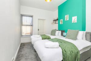 twee bedden in een kamer met groen en wit bij Spacious and Comfy 4 Bed House, Free Parking, Wifi in Birkenhead