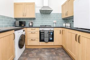 a kitchen with wooden cabinets and a washer and dryer at Spacious and Comfy 4 Bed House, Free Parking, Wifi in Birkenhead