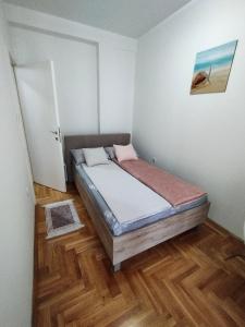 ein Schlafzimmer mit einem Bett in einem Zimmer mit Holzböden in der Unterkunft Stan na dan Sanja in Novi Sad
