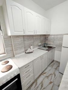 eine weiße Küche mit weißen Schränken und einem Waschbecken in der Unterkunft Stan na dan Sanja in Novi Sad