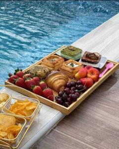 una bandeja de comida en una mesa junto a una piscina en شاليه فراشة en Al Ahsa