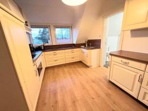 a large kitchen with white cabinets and wooden floors at Ferienwohnung Wilhelm in Steyerberg