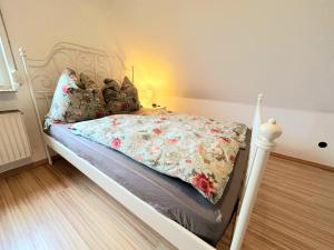 a white bed with a floral comforter in a bedroom at Ferienwohnung Wilhelm in Steyerberg