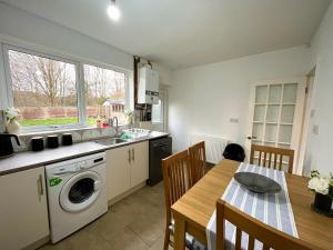 een keuken met een tafel en een wasmachine bij Cosy 4-Bed House in Manchester in Manchester