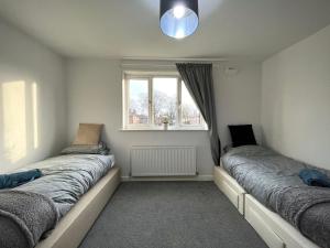 Cosy 4-Bed House in Manchester في مانشستر: سريرين في غرفة مع نافذة