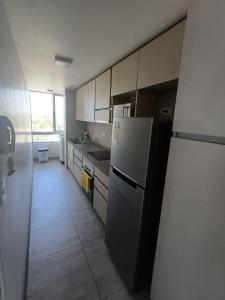 a kitchen with a refrigerator and a sink at Departamento Ines de Suarez, La Florida in Santiago
