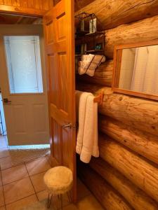 a bathroom in a log cabin with a door and towels at Chalets Terre De l’Orme with Spa tucked away in nature in Saint-Gabriel-De-Valcartier