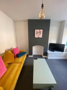 a living room with a yellow couch and a tv at SkylinesAirbnb in Stoke on Trent