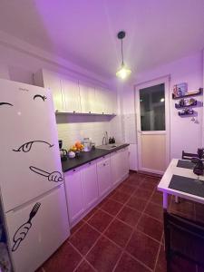 een keuken met witte kasten en een witte koelkast bij Vintage Apartament in Constanţa