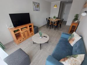 a living room with a blue couch and a television at Departamento Ines de Suarez, La Florida in Santiago