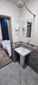 a bathroom with a sink and a mirror and a bed at YASMIN in Samarkand