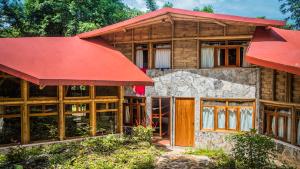 uma casa de madeira com um telhado vermelho em Cabañas Tosepan Kali em Cuetzalan