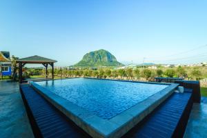 a swimming pool with a mountain in the background at Monteview Stay in Seogwipo
