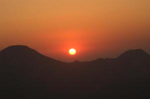 a sunset over mountains with the sun in the sky at Platanian traditional house in Karlovasi