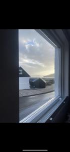 a window with a view of a building and a street at Kirkjatún in Miðvágur