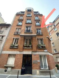 een hoog bakstenen gebouw met een rode pijl erop bij Vincennes Greater Paris JO 2024 Charming flat in Vincennes