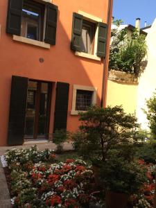 ヴェローナにあるL'Angolino Nascostoの黒いシャッター付きの窓と花のオレンジ色の建物