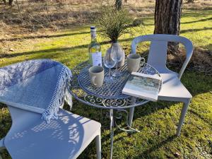 a table and chair with a bottle of wine and a book at Kenama Loghouse and Archaic Sauna in Meremõisa