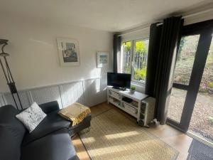 a living room with a couch and a television at Woodland bungalow, fantastic location in Uny Lelant