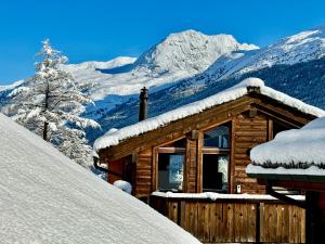 uma cabana de madeira com montanhas cobertas de neve ao fundo em Stirling Luxury Chalet & Spa em Saas-Fee