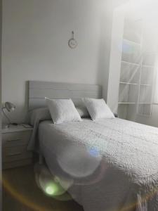 a white bedroom with a bed and a lamp at Novama in O Grove +11 photos