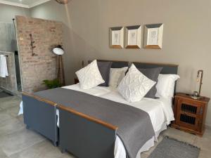 um quarto com uma cama com almofadas brancas e cinzentas em The Lodge on Ilona em Tierpoort
