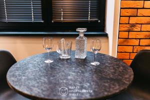 a table with two wine glasses and a bottle on it at Happy Nest - Apartamenty Happy Mielec in Mielec