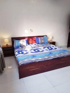 a bed in a room with two night stands and lamps at Appartement moderne K WhiteRed à pk10, Cotonou in Cotonou