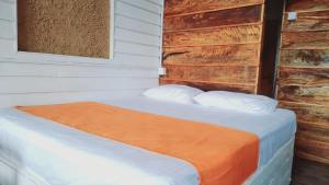 a bed with an orange blanket and two pillows at Dins Nature Villa in Elgiriya